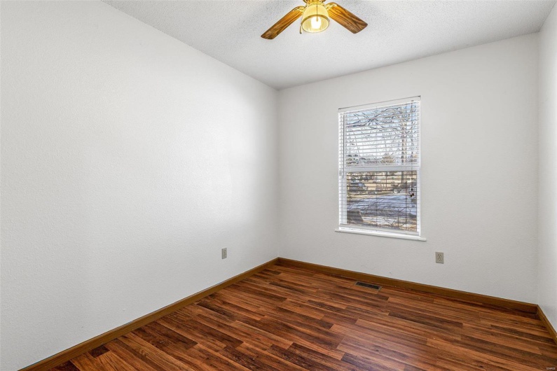 Unfurnished room with dark wood-type flooring and ceiling fan
