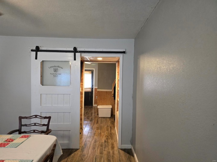 Hallway featuring dark wood-type flooring, a barn door, and a textured ceiling