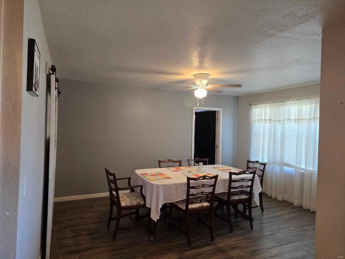 Dining area with ceiling fan, dark hardwood / wood-style floors, a textured ceiling, and a barn door