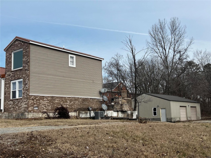 View of side of home featuring an outbuilding, a garage, a yard, and central AC