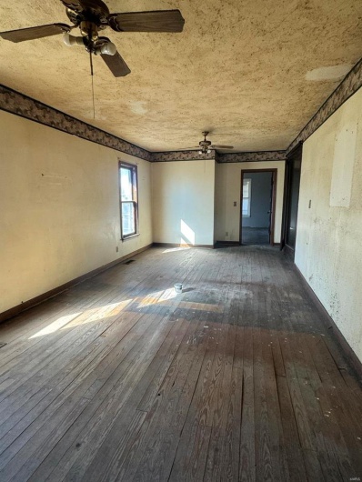 Unfurnished room featuring dark wood-type flooring and ceiling fan
