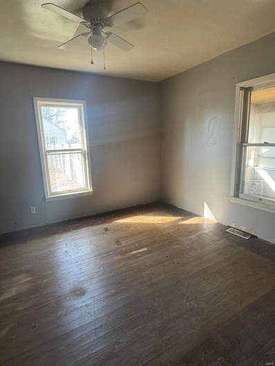 Empty room featuring dark wood-type flooring and ceiling fan