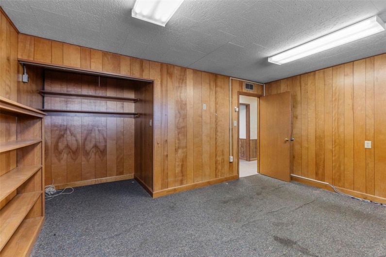 Carpeted empty room featuring wooden walls