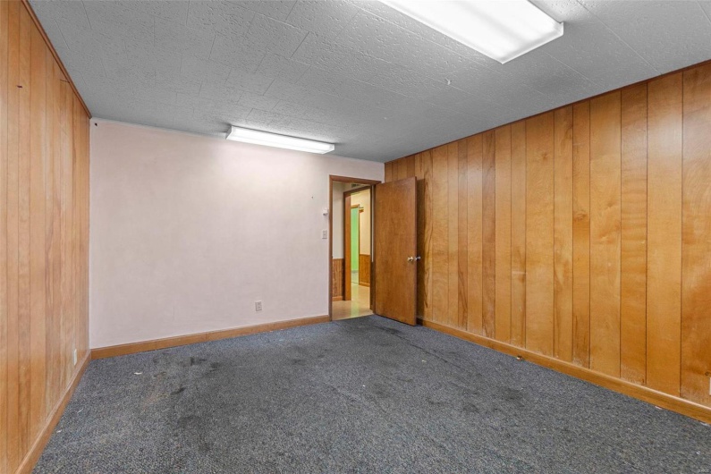 Spare room featuring dark carpet and wooden walls