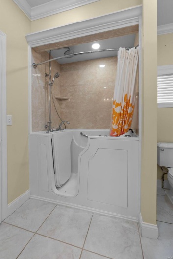 Bathroom with ornamental molding, separate shower and tub, tile patterned floors, and toilet