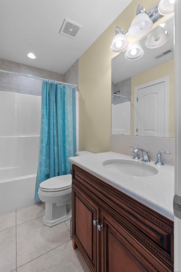 Full bathroom with vanity, shower / tub combo with curtain, tile patterned floors, and toilet