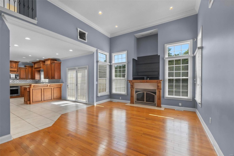 Unfurnished living room with a healthy amount of sunlight, ornamental molding, a towering ceiling, and light wood-type flooring