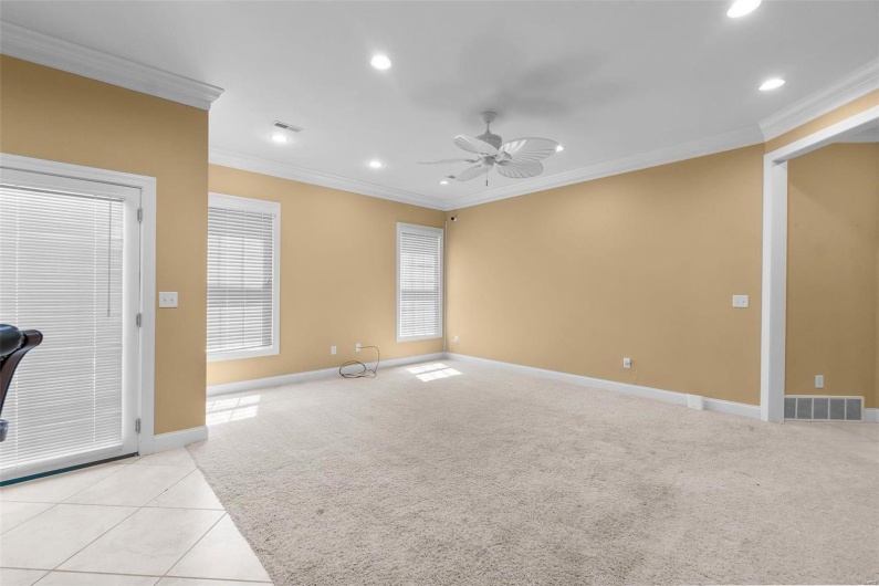 Unfurnished living room featuring light colored carpet, ornamental molding, and ceiling fan