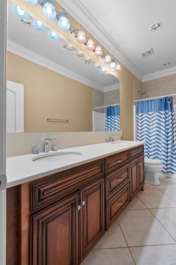 Bathroom featuring tile patterned floors, toilet, ornamental molding, vanity, and curtained shower