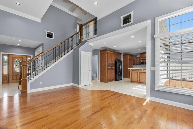 Unfurnished living room with ornamental molding, light hardwood / wood-style floors, a healthy amount of sunlight, and a high ceiling