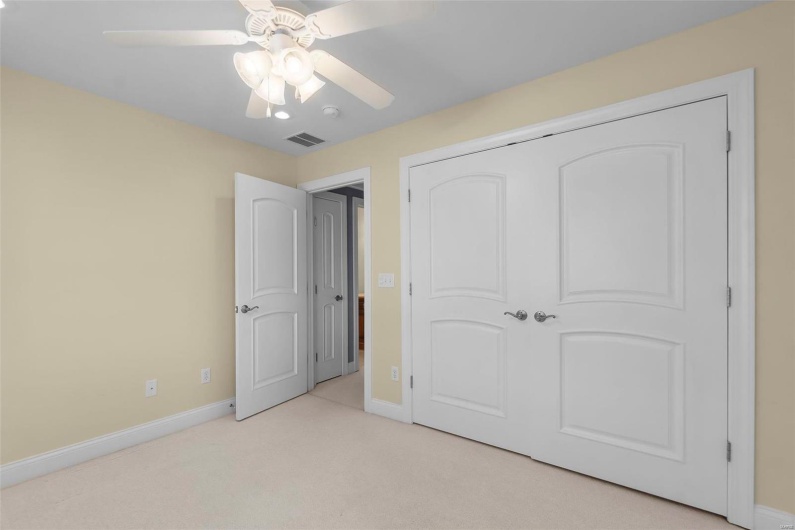 Bedroom with light colored carpet, ceiling fan, and a closet