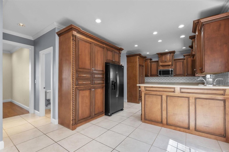 Kitchen with ornamental molding, light tile patterned floors, refrigerator with ice dispenser, and backsplash