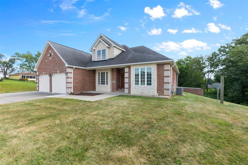 View of front of house with central AC unit, a garage, and a front lawn