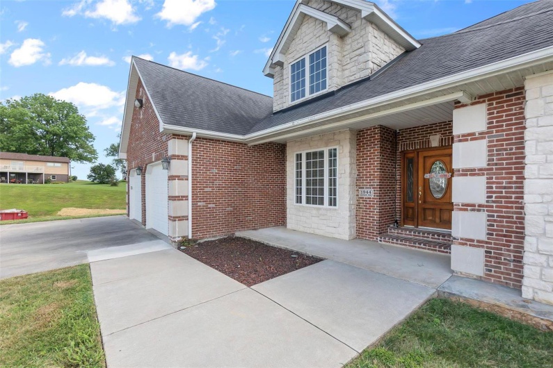 Doorway to property with a garage and a lawn