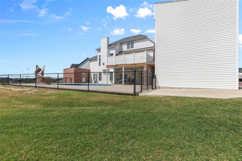 Back of property featuring a yard and an empty pool