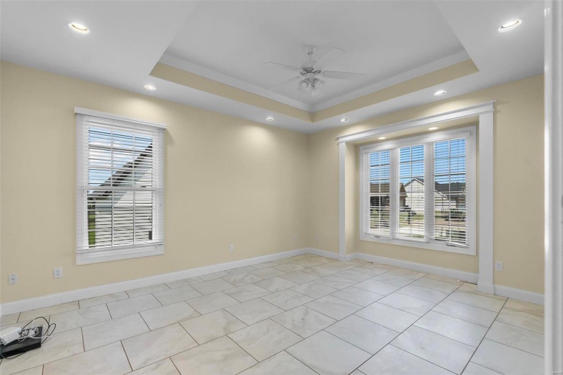Tiled empty room featuring a raised ceiling, crown molding, and ceiling fan