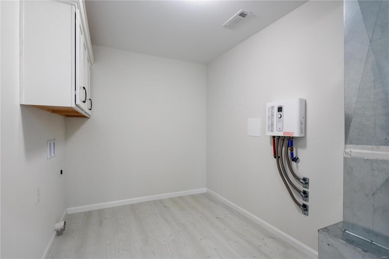 Laundry room with hookup for a washing machine, light hardwood / wood-style floors, and cabinets