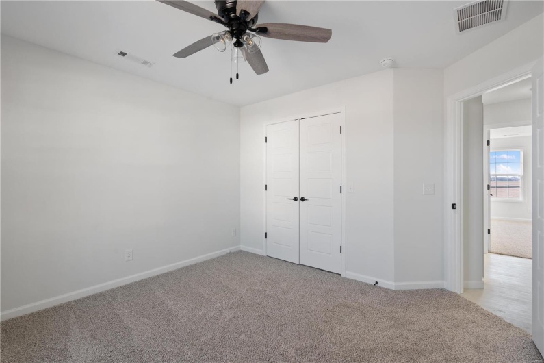 Unfurnished bedroom with light carpet, ceiling fan, and a closet