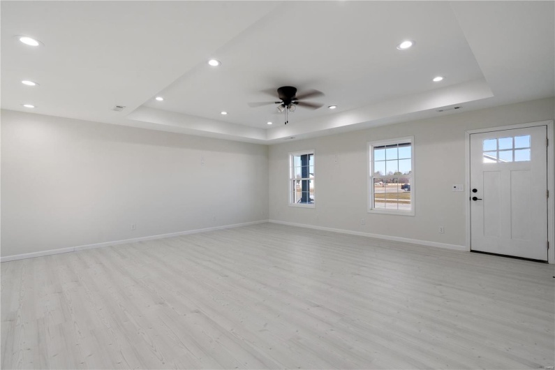 Unfurnished room featuring ceiling fan, a raised ceiling, and light hardwood / wood-style flooring