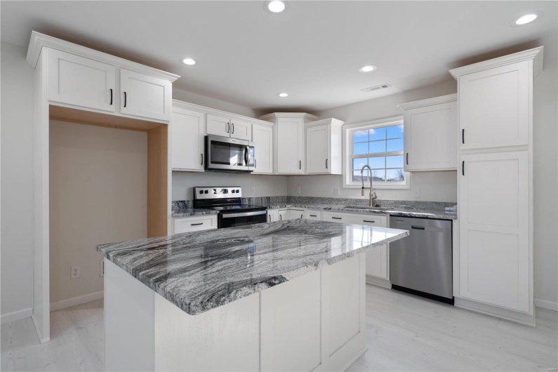 Kitchen featuring a kitchen island, white cabinetry, appliances with stainless steel finishes, and sink
