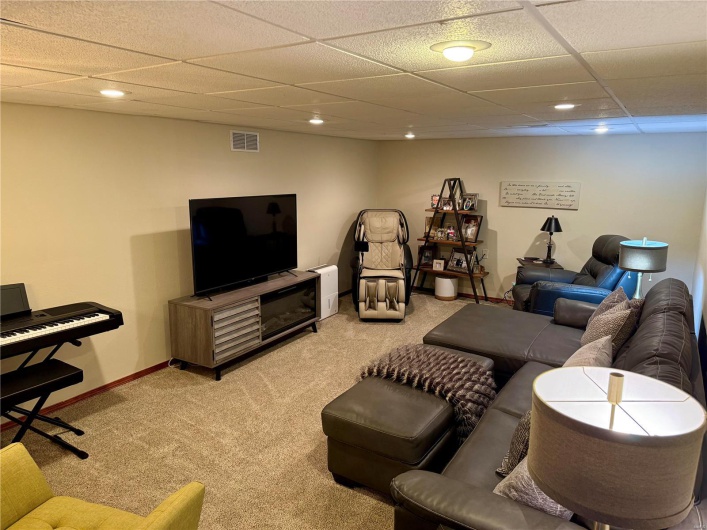 Living room featuring a drop ceiling and light colored carpet