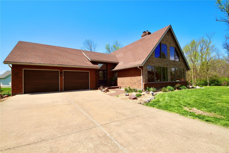 View of front facade featuring a garage, roof with shingles, a front lawn, brick siding, and driveway