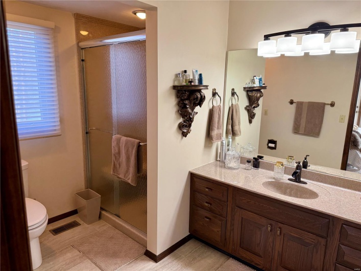 Bathroom with vanity, baseboards, toilet, a shower stall, and visible vents