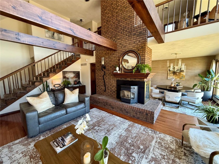 Great room featuring hardwood / wood-style flooring, a towering ceiling, a notable chandelier, and beam ceiling