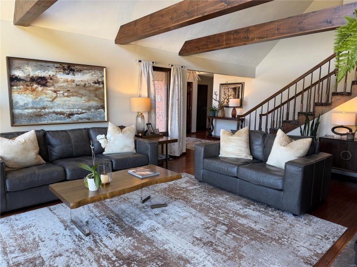 Great room with dark wood-type flooring and lofted ceiling with beams