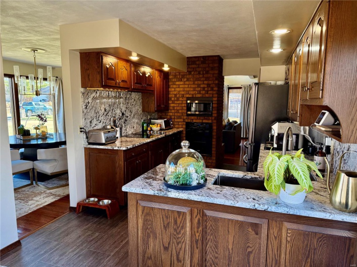 Kitchen featuring light stone counters, kitchen peninsula, decorative backsplash, and black appliances