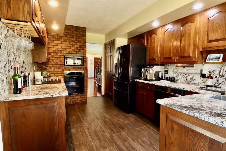 Kitchen featuring a sink, backsplash, black appliances, and light stone countertops