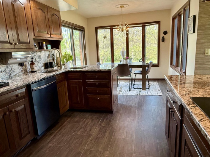 Kitchen with dishwasher, a sink, and light stone countertops