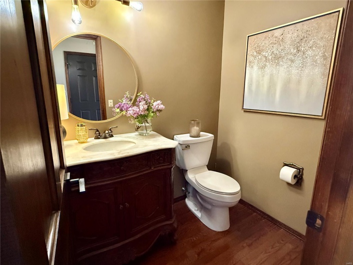 Bathroom featuring toilet, wood finished floors, vanity, and baseboards