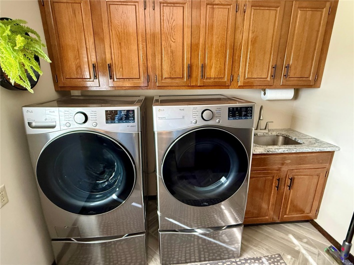 Laundry area featuring separate washer and dryer, light wood finished floors, a sink, and cabinet space