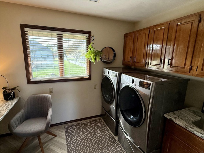 Clothes washing area featuring light wood-style floors, washing machine and dryer, baseboards, and cabinet space