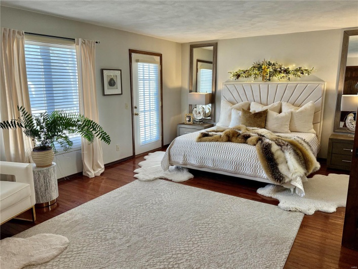 Bedroom featuring access to exterior, dark hardwood / wood-style floors, and a textured ceiling