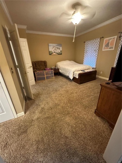 Bedroom with crown molding, dark carpet, and ceiling fan