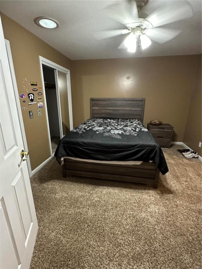 Bedroom with ceiling fan, a closet, a textured ceiling, and carpet flooring