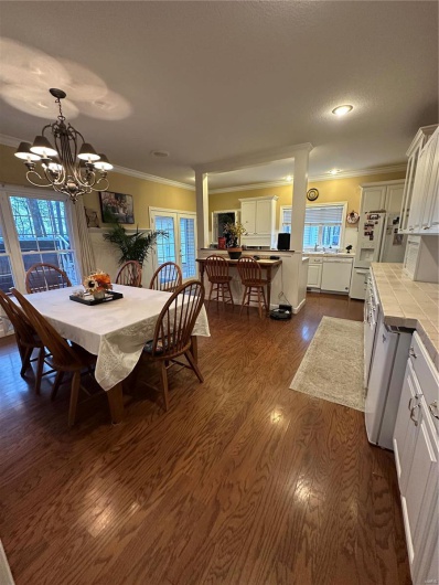 Dining area featuring dark wood-type flooring, ornamental molding, and a notable chandelier