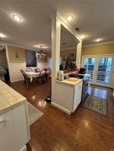 Kitchen with ornamental molding, stove, white cabinets, and dark hardwood / wood-style flooring