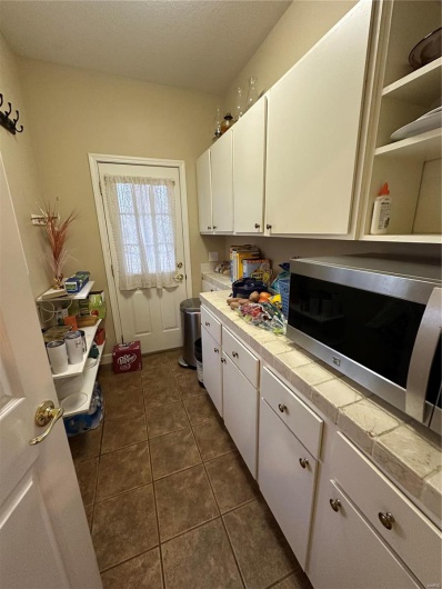 Kitchen with dark tile patterned floors, white cabinetry, tile countertops, and a textured ceiling