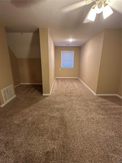 Additional living space with ceiling fan, carpet flooring, and a textured ceiling