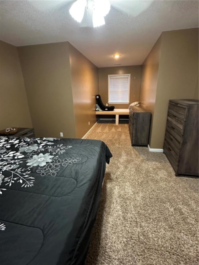 Bedroom featuring ceiling fan, carpet, and a textured ceiling