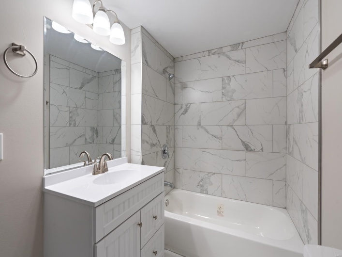 Bathroom with tiled shower / bath combo and vanity