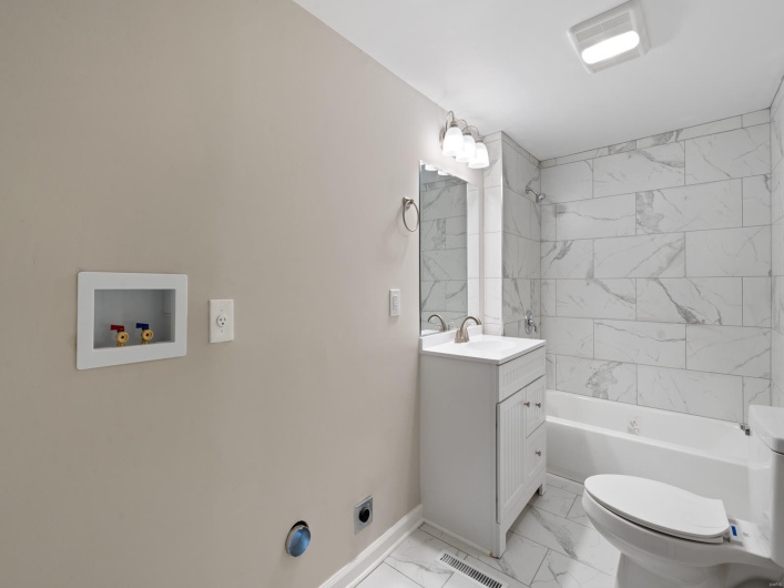 Full bathroom with vanity, tiled shower / bath combo, and toilet
