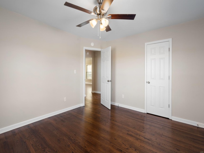 Unfurnished bedroom with dark wood-type flooring and ceiling fan