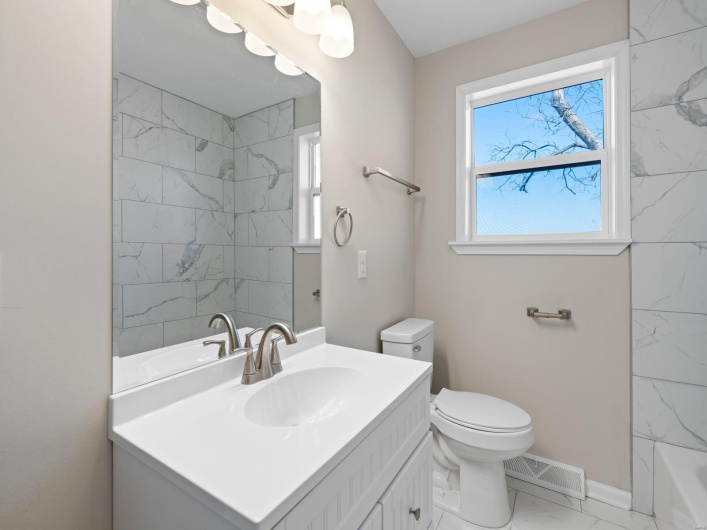 Full bathroom with vanity, tiled shower / bath combo, a wealth of natural light, and toilet