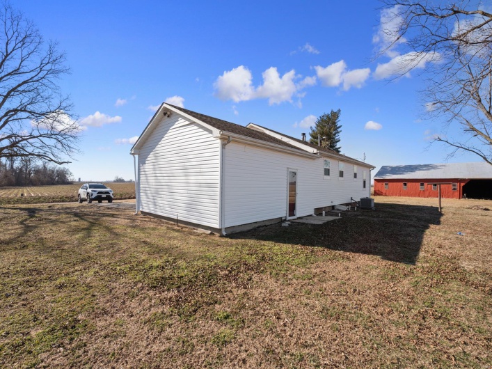 View of side of property featuring a yard and central AC unit
