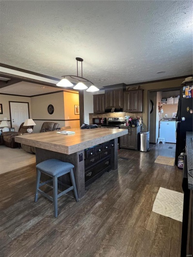 Kitchen with pendant lighting, butcher block counters, a kitchen bar, dark brown cabinetry, and dark wood-type flooring