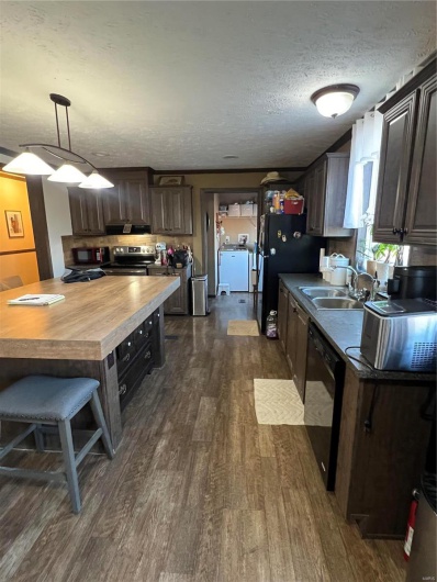 Kitchen with hanging light fixtures, dark brown cabinets, sink, and dishwashing machine